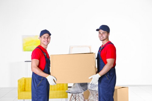 Professional movers carrying furniture near a modern London apartment block